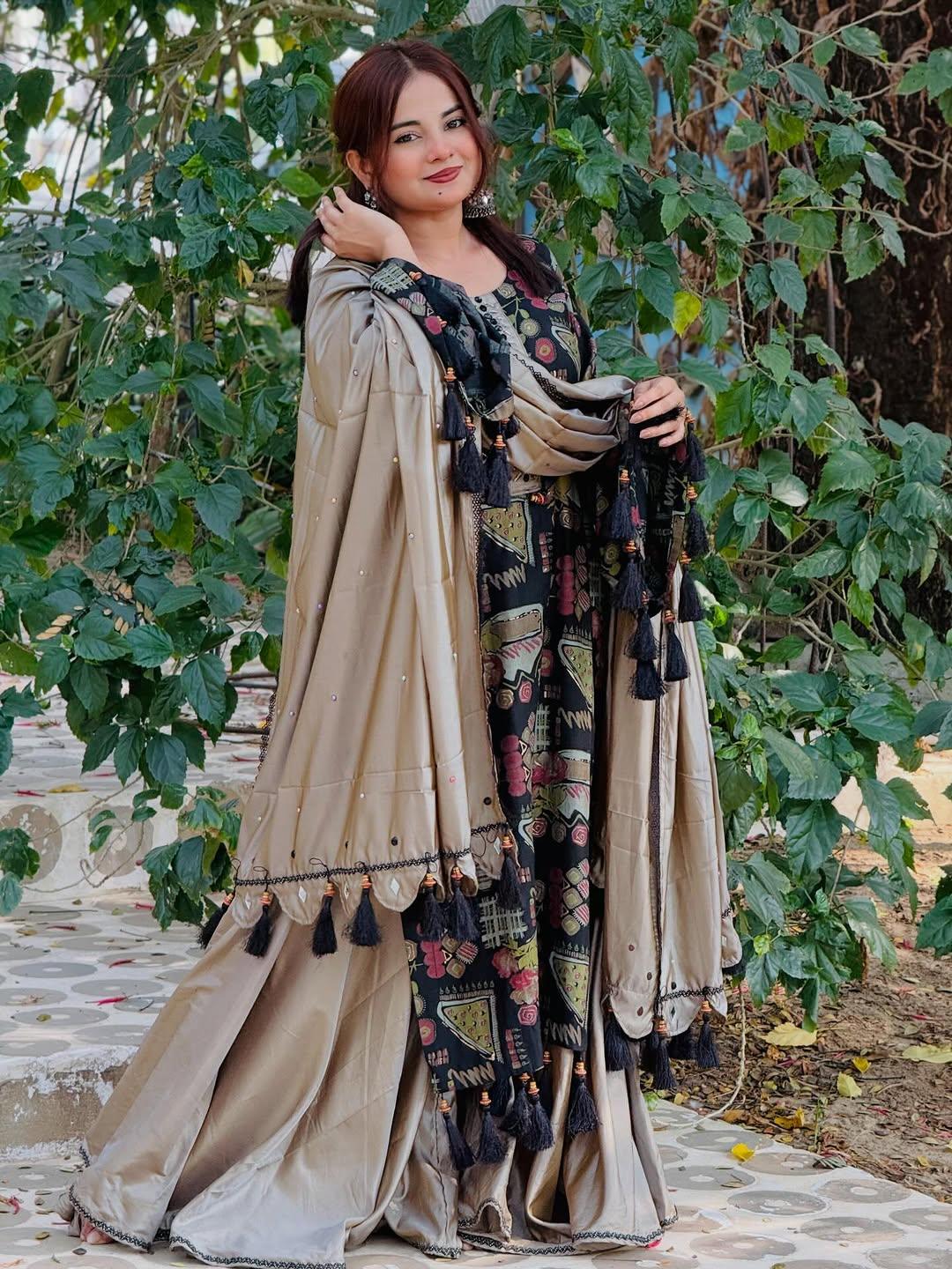Woman in beige and black traditional embroidered dress with tassels, standing outdoors