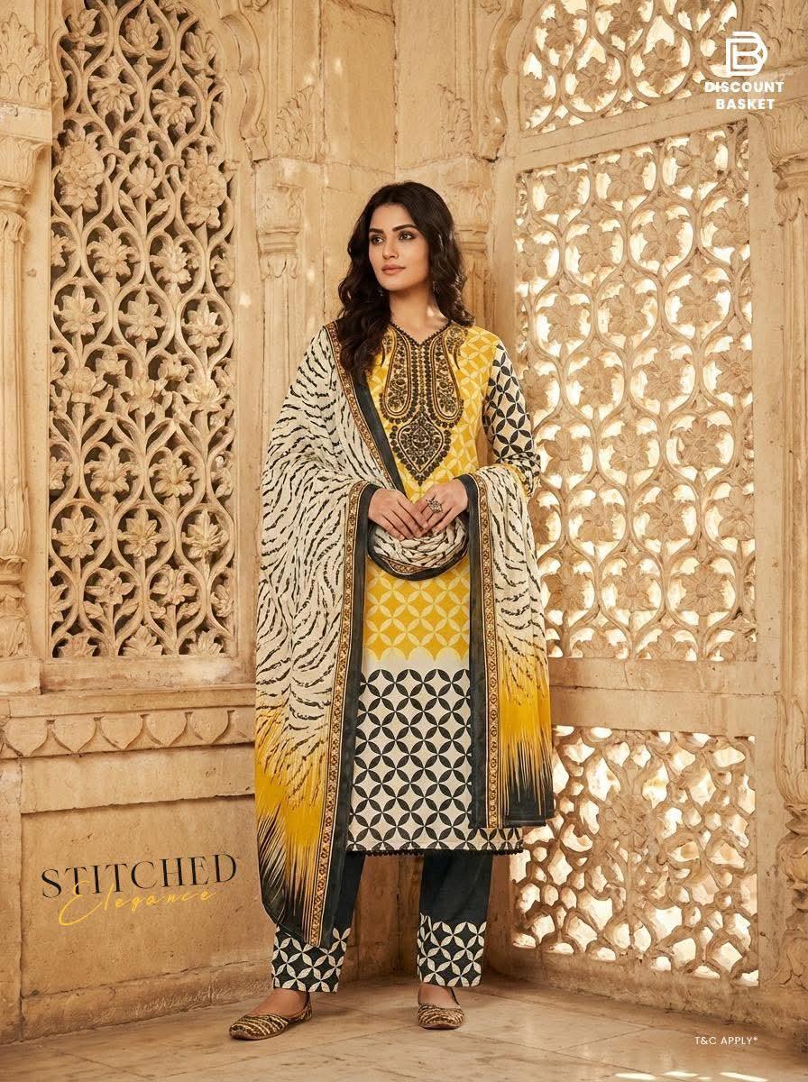 Woman in yellow and black printed stitched salwar kameez set with dupatta, standing by ornate wall