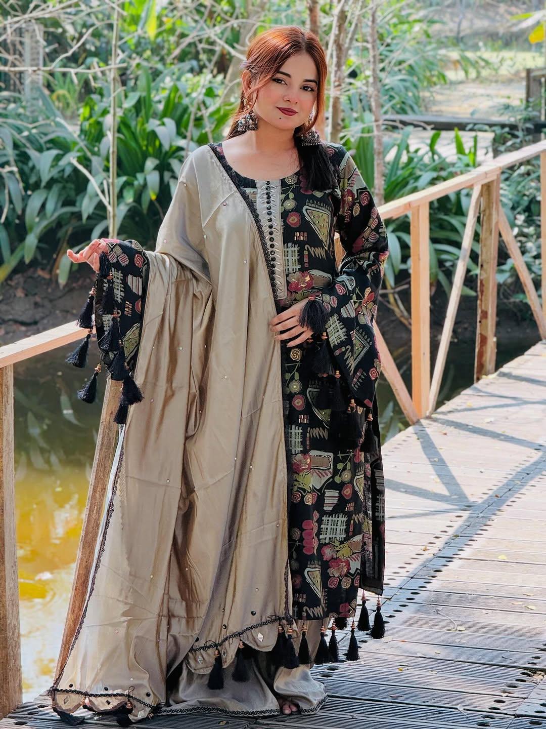 Woman wearing elegant beige and black ethnic dress with printed patterns, posing on a wooden bridge outdoors