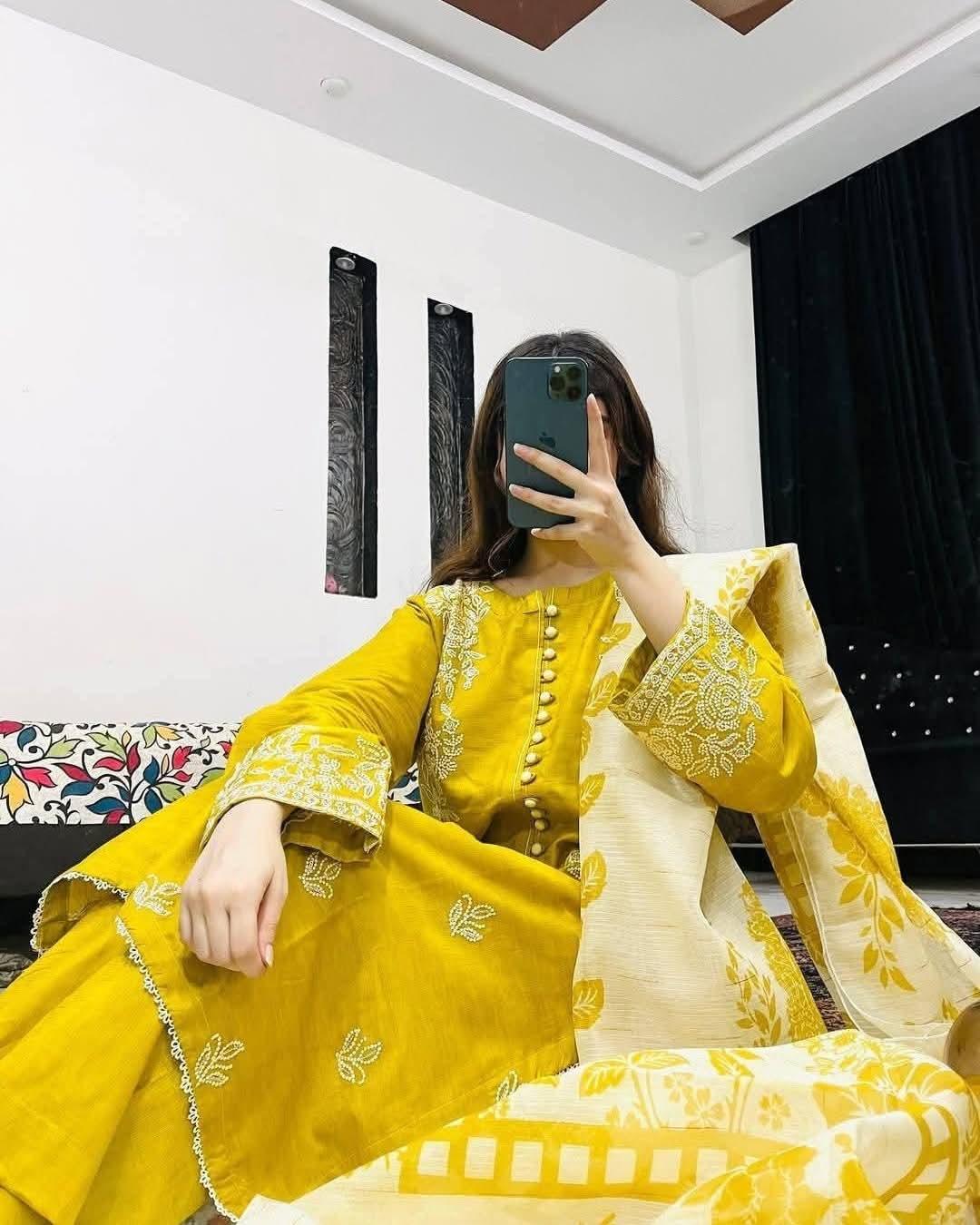 Woman in yellow embroidered traditional dress with cream and yellow printed dupatta indoors