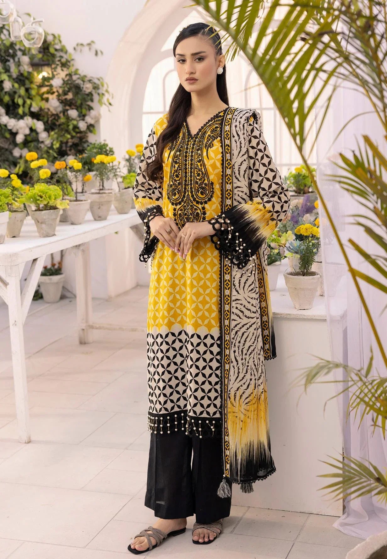 Woman wearing yellow and black printed ethnic suit with black trousers in a floral indoor setting