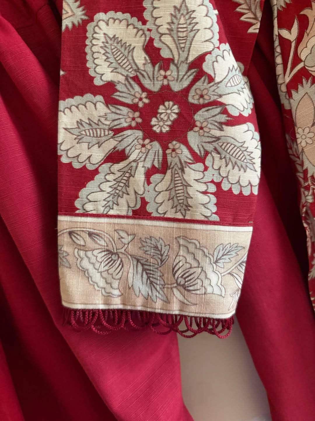 Red fabric with beige floral block print and decorative border, traditional textile design